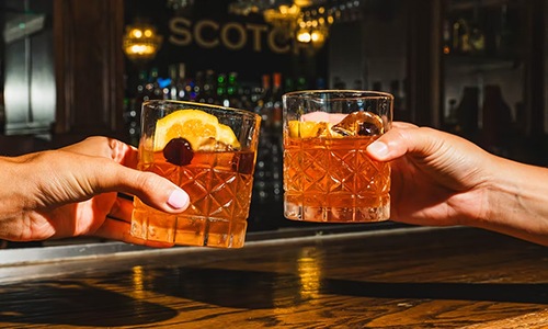 people holding glasses of whiskey